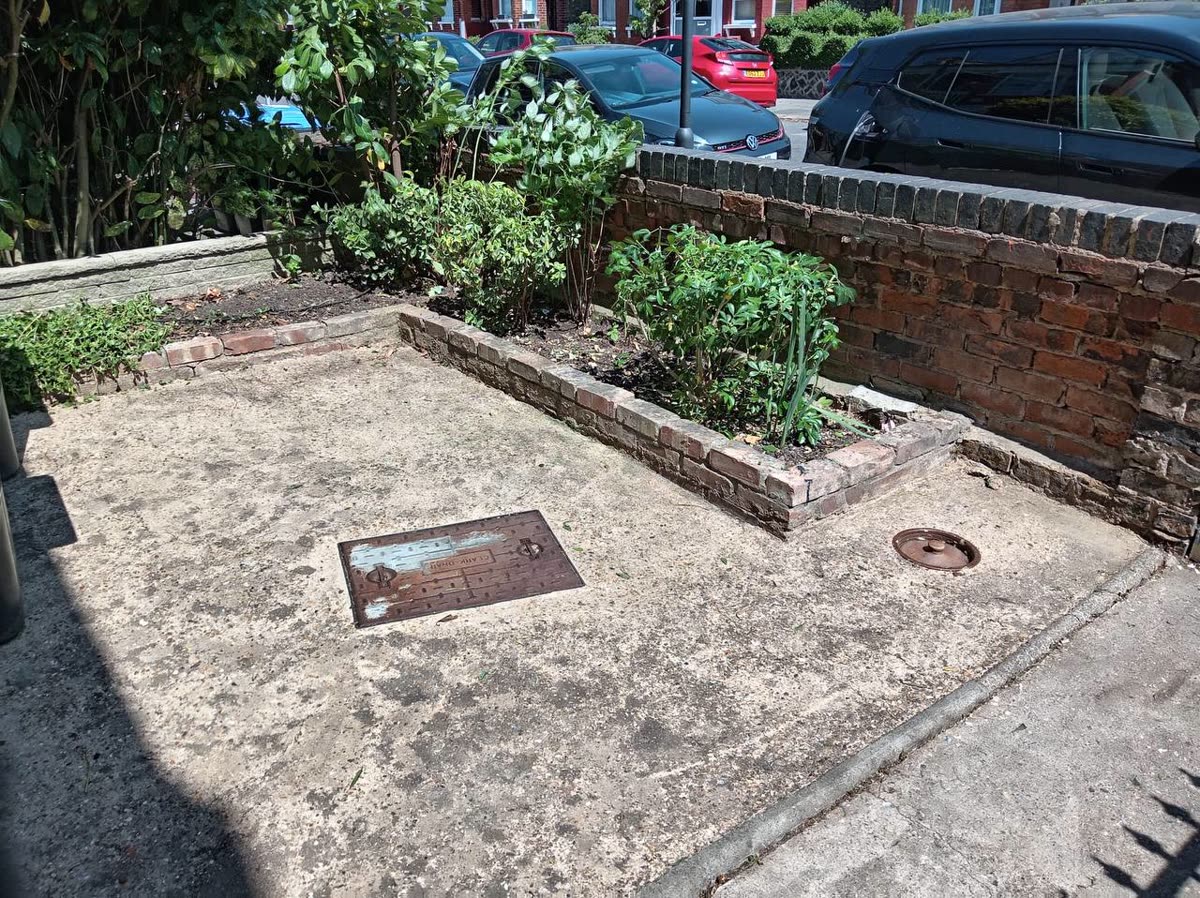 Overgrown North London front garden before — bare paving and a tired raised bed